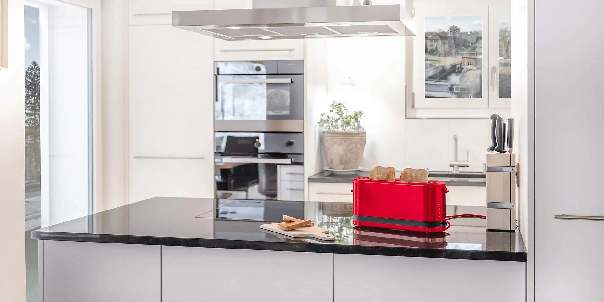 Ein roter Toaster mit zwei Toasts steht auf einer Küchenablage