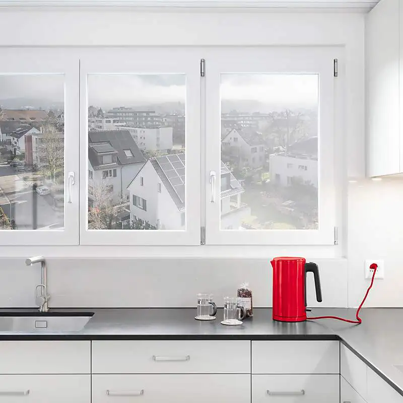 Ein roter Wasserkocher steht auf einer Küche mit Ausblick auf ein Quartier